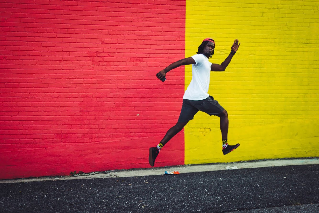 Ceesay running by a brick wall painted red and yellow